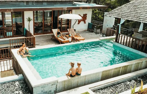 family swimming in pool villa